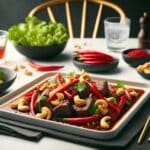 Thai beef dish with red chili and cashew nuts displayed on a sleek, rectangular white plate