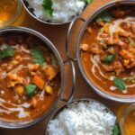 Vegan Curry Recipe in silver balti stle dishes with bowls of rice on a wooden table