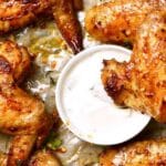 Chicken wings on a baking tray with coriander and a creamy dipping sauce