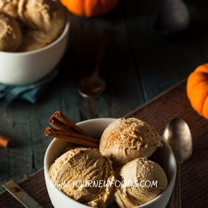 pumpkin ice ream in a blue bowl with to pumpkins in the background