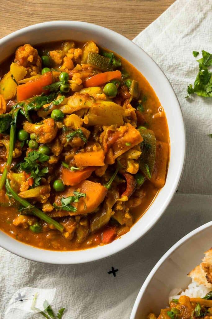Vegan curry with peas, beans and carrots in a white bowl