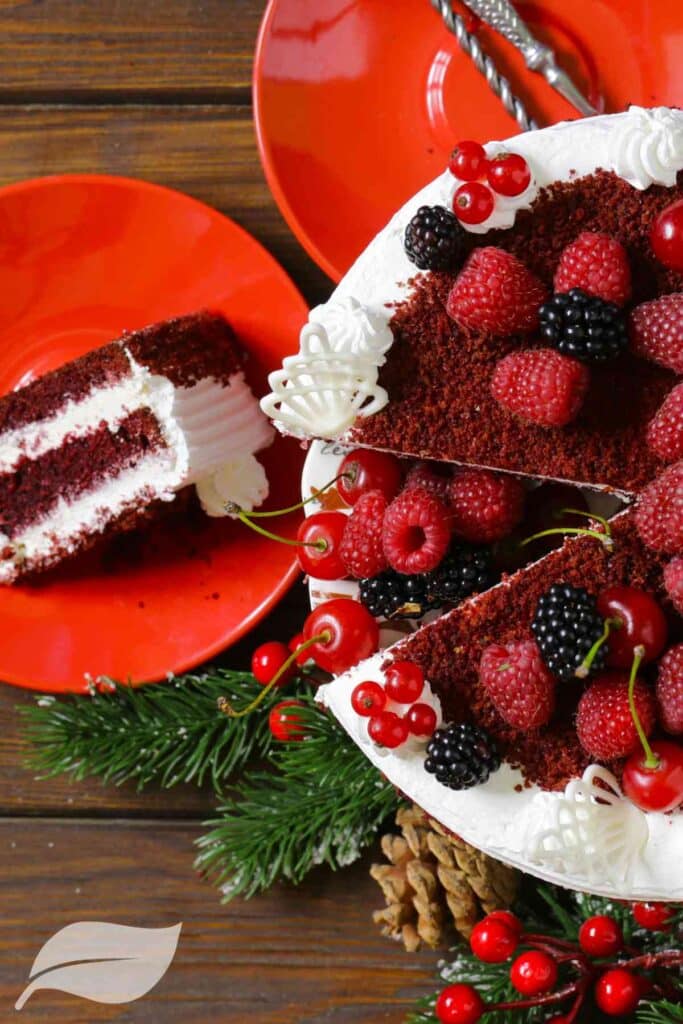 cake with fresh raspberries on with a slice of cake on a side plate