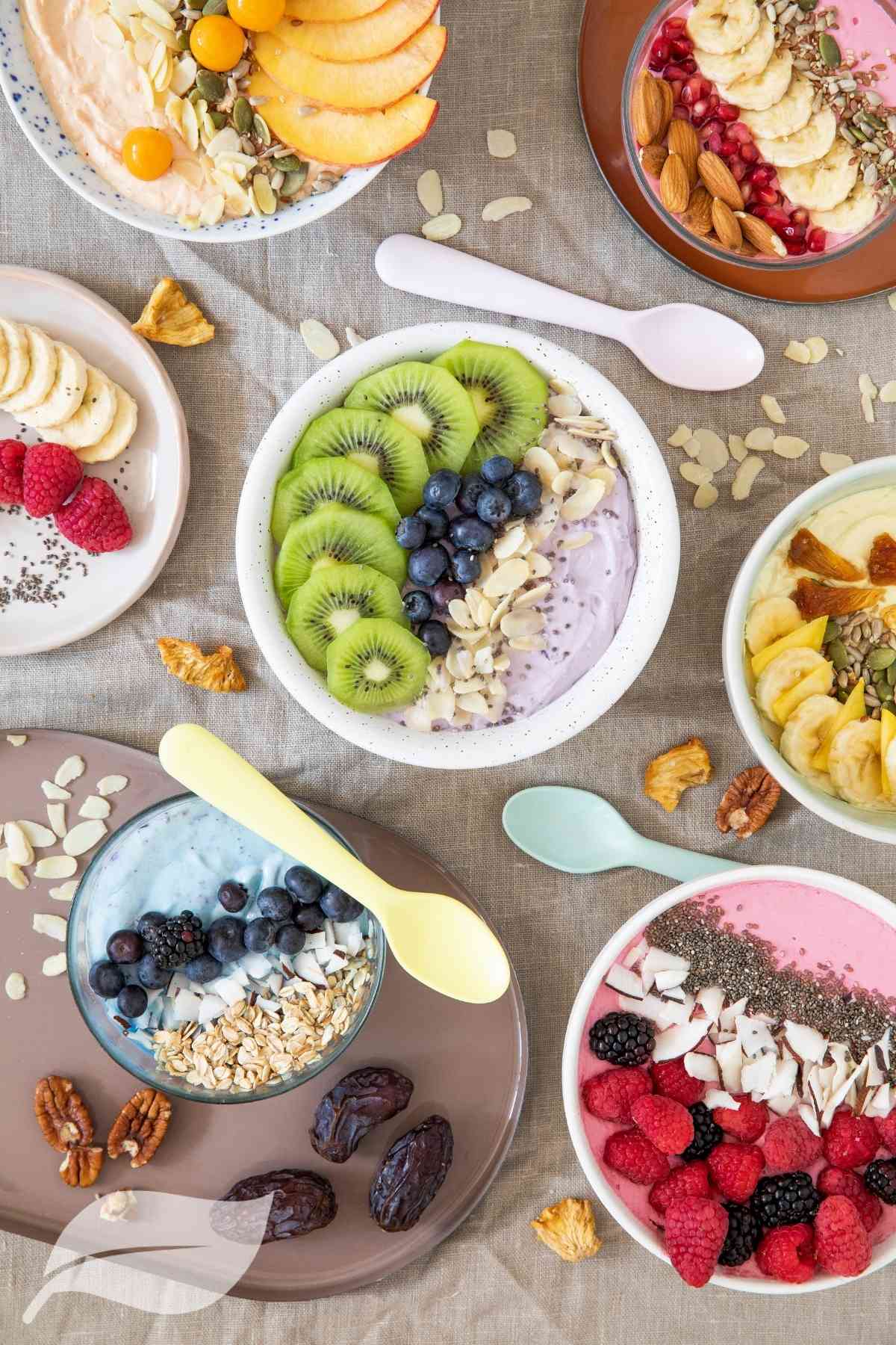 a selection of smoothie bowls with slices of fruit on top