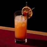 orange tequila cocktail with straw and umbrella