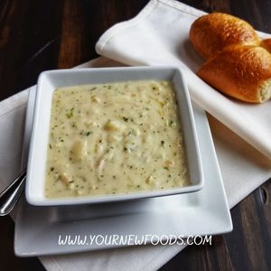 Instant pot seafood chowder in a white square bowl with a bread roll