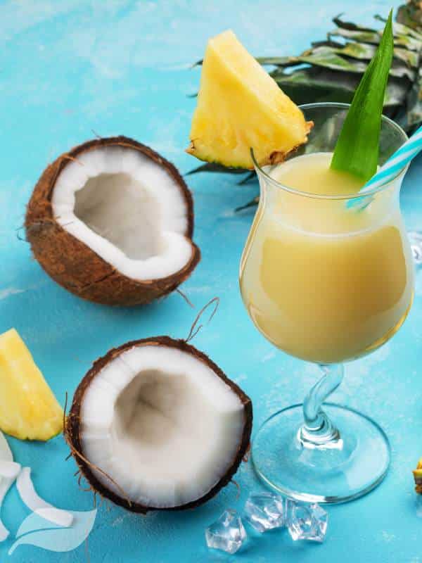 pina colada with a coconut in a half next to the glass