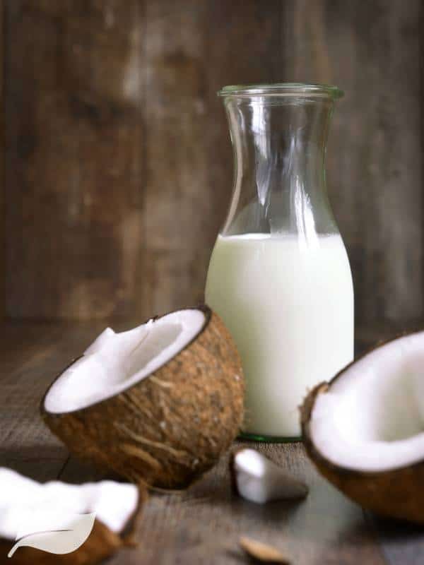 coconut in half with a jug of coconut milk